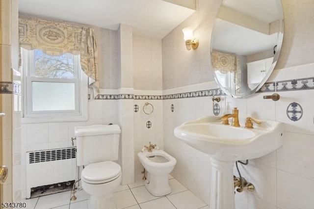 bathroom featuring radiator, a bidet, tile walls, toilet, and tile patterned floors