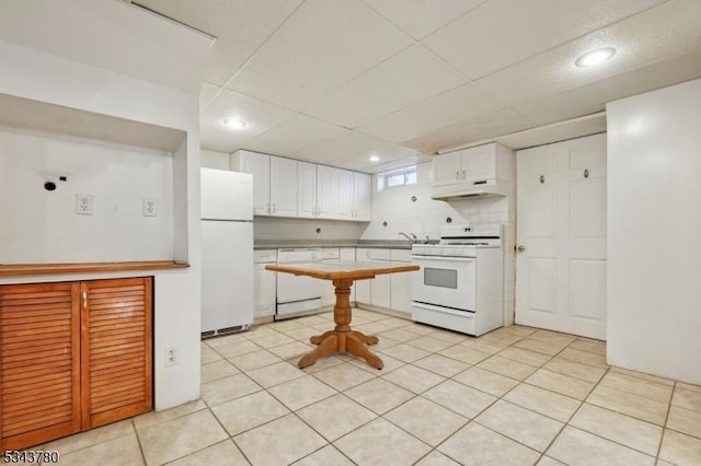 kitchen featuring white appliances, white cabinets, light tile patterned flooring, and under cabinet range hood