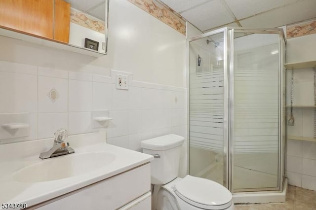 bathroom with vanity, a shower stall, and tile walls