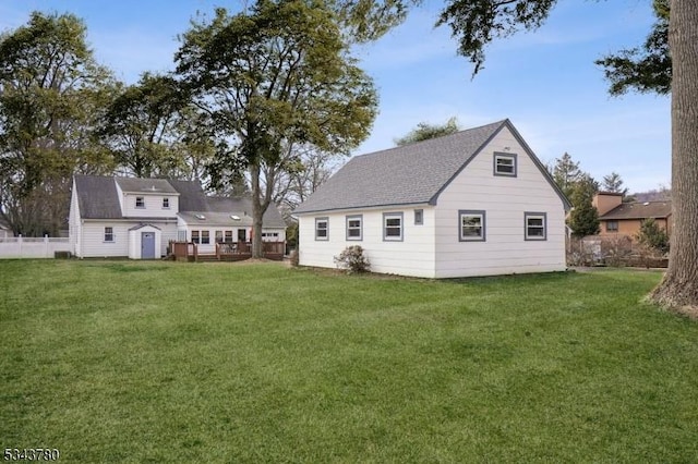 back of house featuring an outdoor structure, a yard, and fence