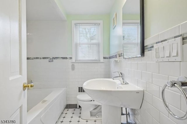 bathroom with toilet, tile walls, and a bath