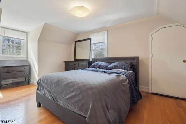 bedroom featuring wood finished floors, baseboards, and vaulted ceiling