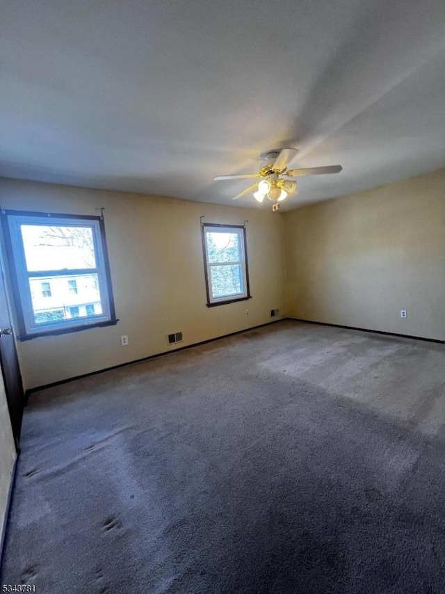 carpeted empty room featuring visible vents and ceiling fan