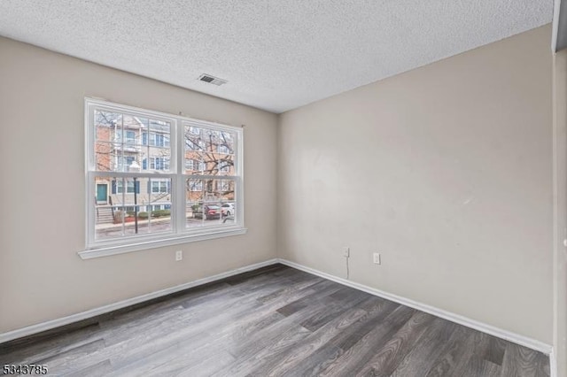 unfurnished room featuring dark wood finished floors, visible vents, a textured ceiling, and baseboards