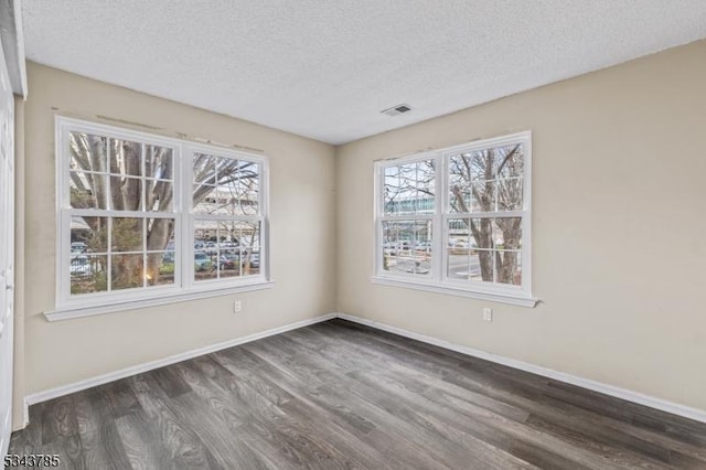 spare room with visible vents, baseboards, a textured ceiling, and wood finished floors