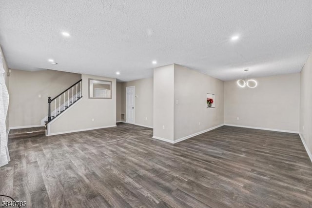 unfurnished living room featuring baseboards, dark wood finished floors, stairs, recessed lighting, and a textured ceiling