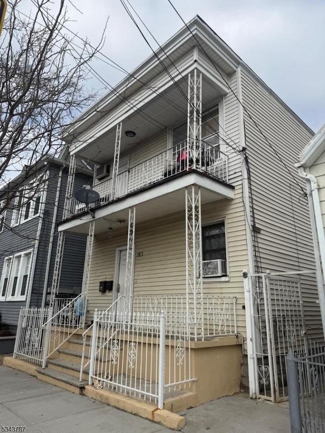 view of front of property with a fenced front yard, covered porch, and a balcony