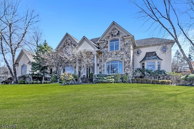 french country style house featuring a front lawn, stone siding, and stucco siding