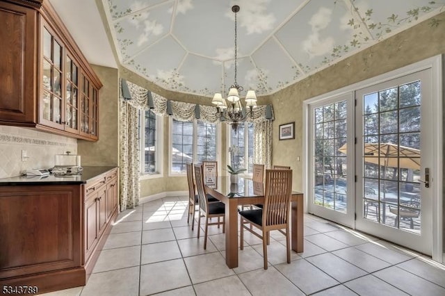 dining space with vaulted ceiling, a notable chandelier, and light tile patterned floors