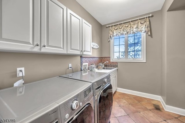 clothes washing area featuring visible vents, cabinet space, baseboards, and washing machine and dryer