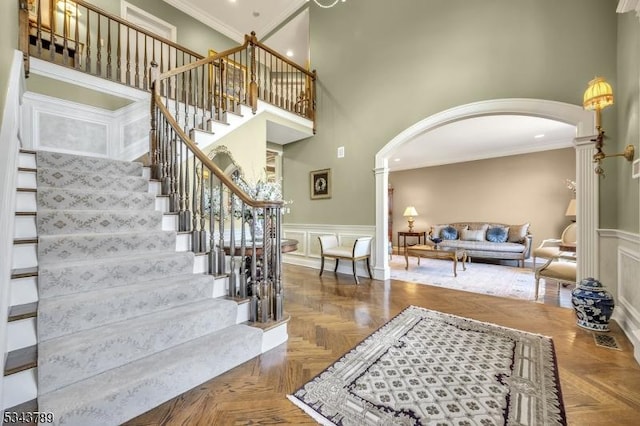 foyer entrance with arched walkways, a decorative wall, ornamental molding, and decorative columns