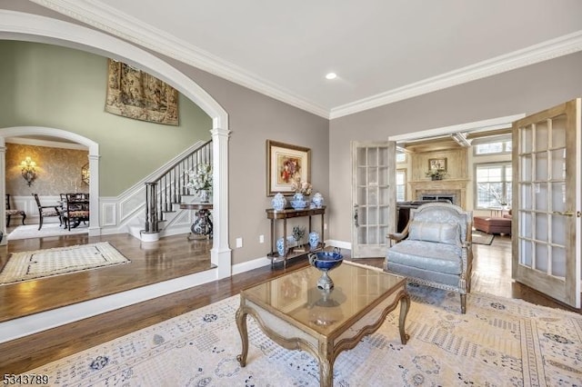 living room featuring ornamental molding, wood finished floors, stairway, arched walkways, and ornate columns