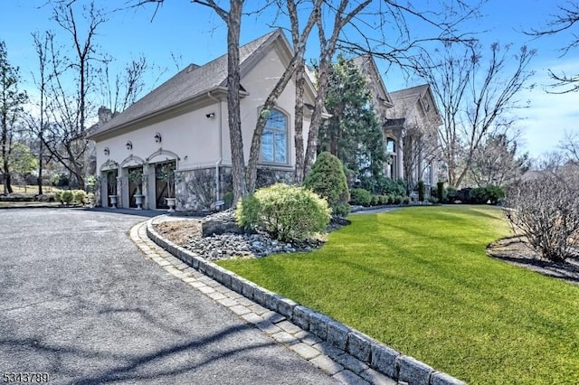 view of home's exterior with gravel driveway, a carport, a yard, and stucco siding