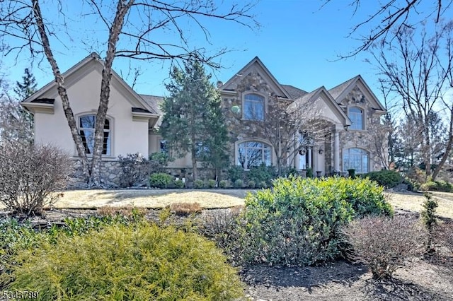 french country inspired facade with stone siding and stucco siding