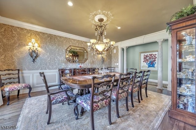 dining area featuring wallpapered walls, ornamental molding, wainscoting, wood finished floors, and a decorative wall