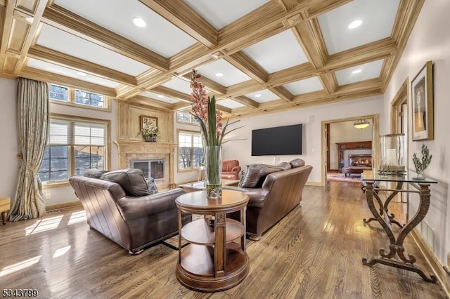 living area with a glass covered fireplace, beamed ceiling, coffered ceiling, and wood finished floors