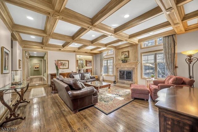 living area featuring beam ceiling, coffered ceiling, and wood finished floors