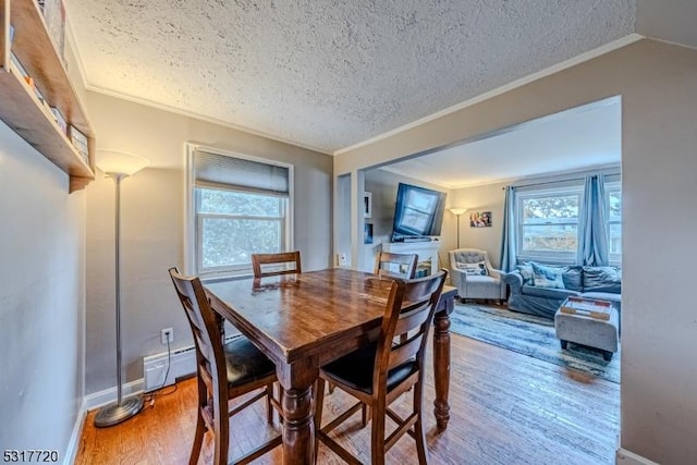 dining room with a wealth of natural light, a textured ceiling, wood finished floors, and ornamental molding