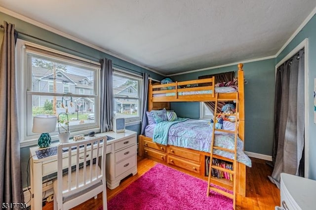 bedroom featuring baseboards, wood finished floors, and crown molding