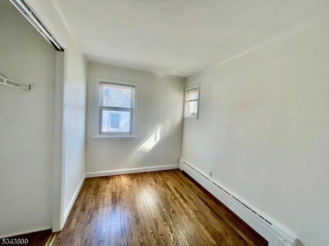 interior space featuring a closet, baseboards, baseboard heating, and hardwood / wood-style floors