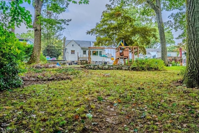 rear view of house with a lawn and a playground