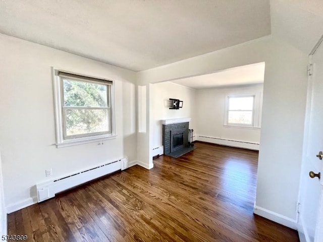 unfurnished living room featuring baseboard heating, dark wood-style flooring, a glass covered fireplace, and a baseboard radiator