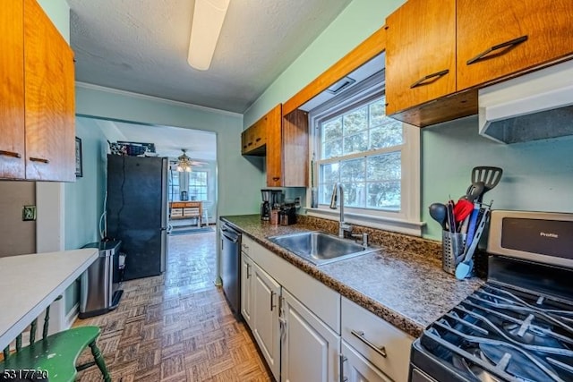 kitchen featuring a ceiling fan, a sink, stainless steel appliances, white cabinets, and a textured ceiling