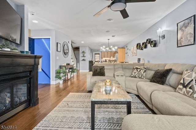 living room with recessed lighting, a glass covered fireplace, ceiling fan with notable chandelier, and wood finished floors