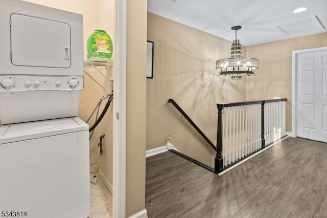 washroom with wood finished floors, baseboards, and stacked washer and dryer