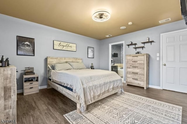 bedroom with visible vents, baseboards, ensuite bath, and wood finished floors