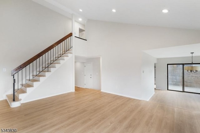 unfurnished living room featuring recessed lighting, high vaulted ceiling, stairs, and wood finished floors