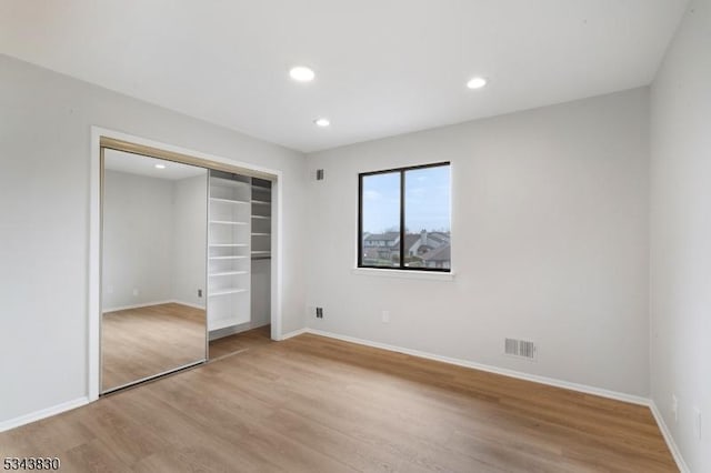 unfurnished bedroom featuring visible vents, baseboards, recessed lighting, light wood-style floors, and a closet