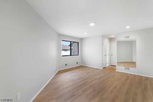 unfurnished room featuring visible vents, light wood-style flooring, and baseboards