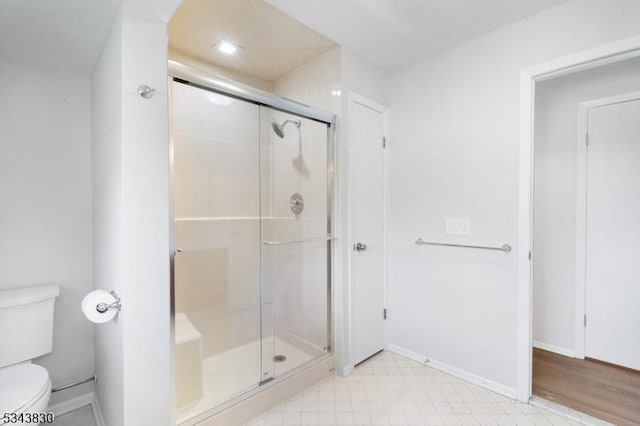 full bath with baseboards, toilet, and a stall shower