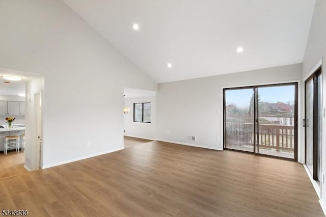 unfurnished living room with recessed lighting, baseboards, high vaulted ceiling, and light wood-style flooring