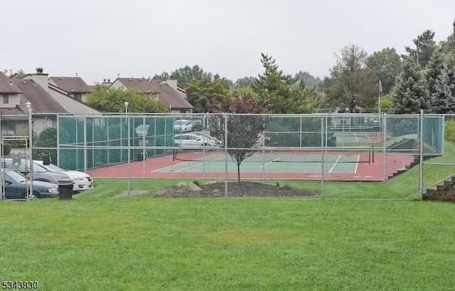 view of tennis court featuring a yard and fence