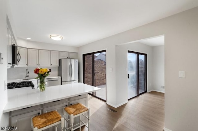 kitchen with visible vents, light wood-style flooring, appliances with stainless steel finishes, a peninsula, and light countertops