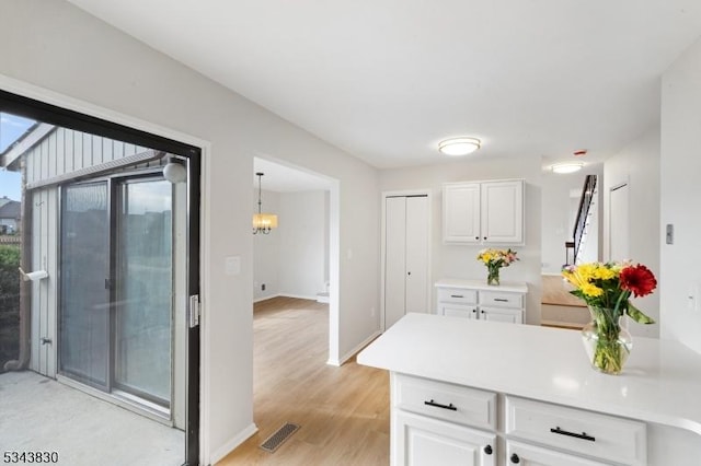 kitchen featuring visible vents, a peninsula, white cabinetry, and light countertops