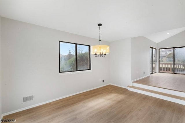 empty room featuring wood finished floors, visible vents, baseboards, lofted ceiling, and a notable chandelier