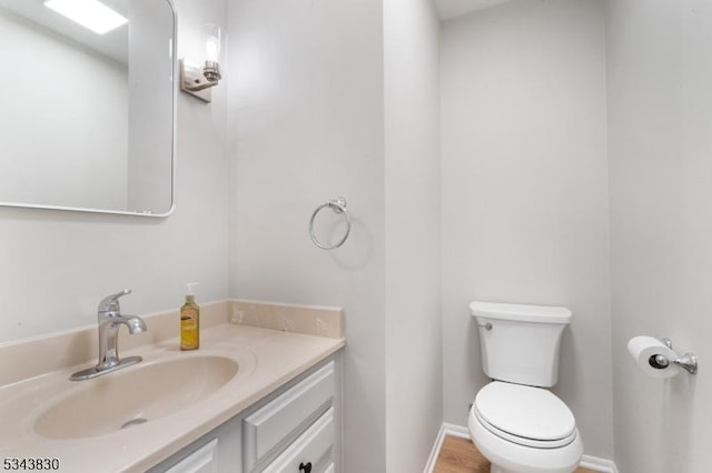 bathroom featuring baseboards, toilet, and vanity