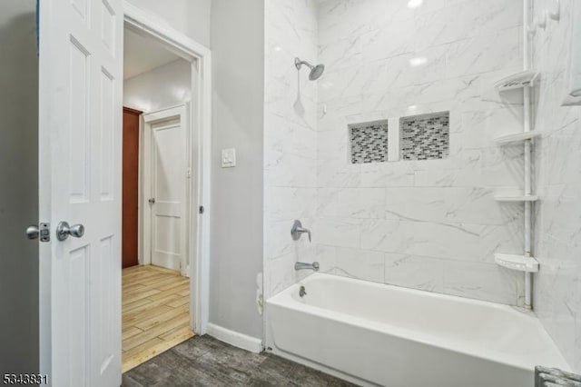 full bath with baseboards, bathing tub / shower combination, and wood finish floors