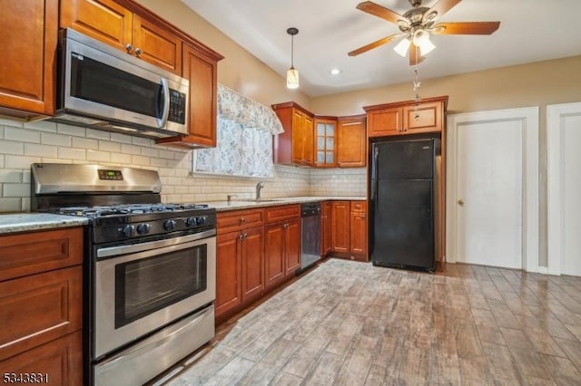 kitchen featuring light stone counters, brown cabinetry, light wood finished floors, stainless steel appliances, and decorative backsplash