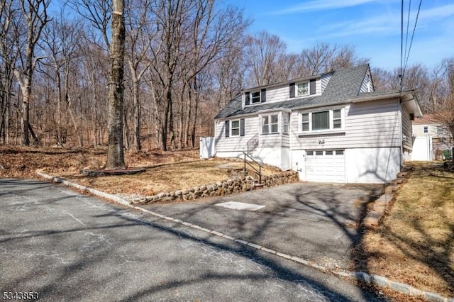 view of front of home featuring an attached garage, driveway, and a shingled roof