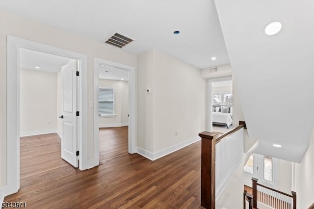 hallway featuring wood finished floors, an upstairs landing, and visible vents