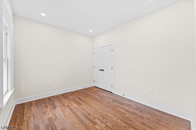 spare room with recessed lighting, baseboards, and wood finished floors