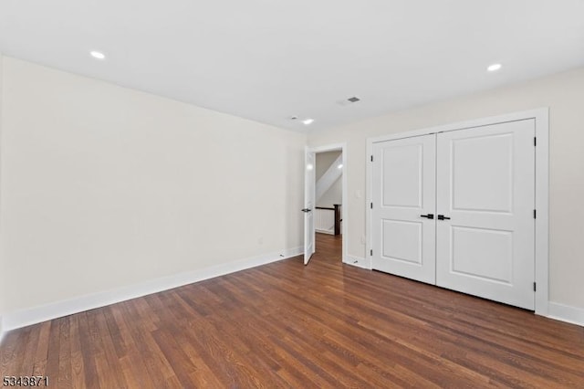 unfurnished bedroom with recessed lighting, a closet, baseboards, and dark wood-style floors