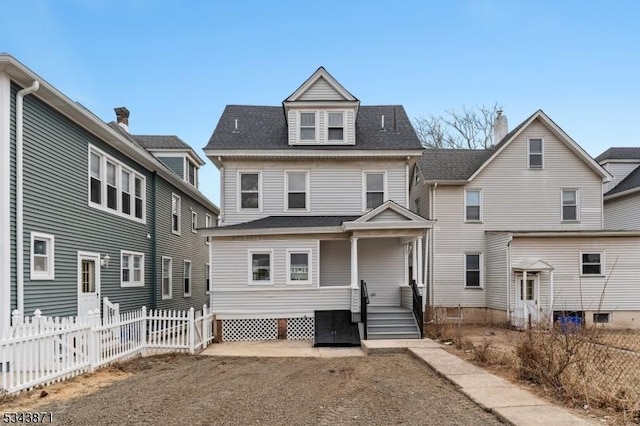 rear view of property with a shingled roof and fence