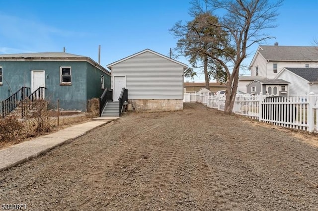 rear view of house with entry steps, fence, and a residential view