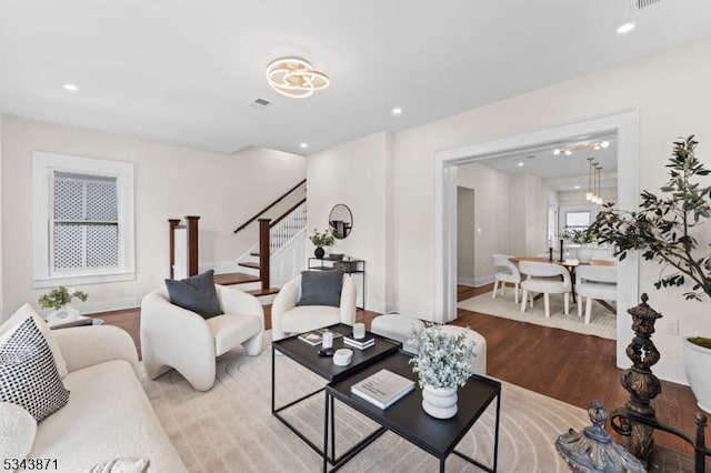 living area featuring wood finished floors, visible vents, baseboards, recessed lighting, and stairs