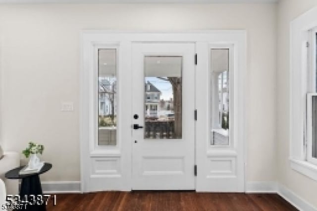 foyer entrance featuring baseboards, dark wood-type flooring, and a healthy amount of sunlight